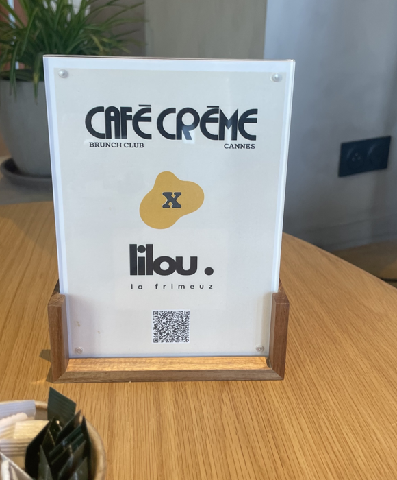 Présentoir avec QR code Café Crème x Lilou la Frimeuz sur une table en bois dans l'hôtel cannois